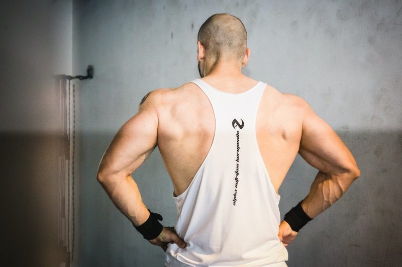 Man with strong back muscles white vest