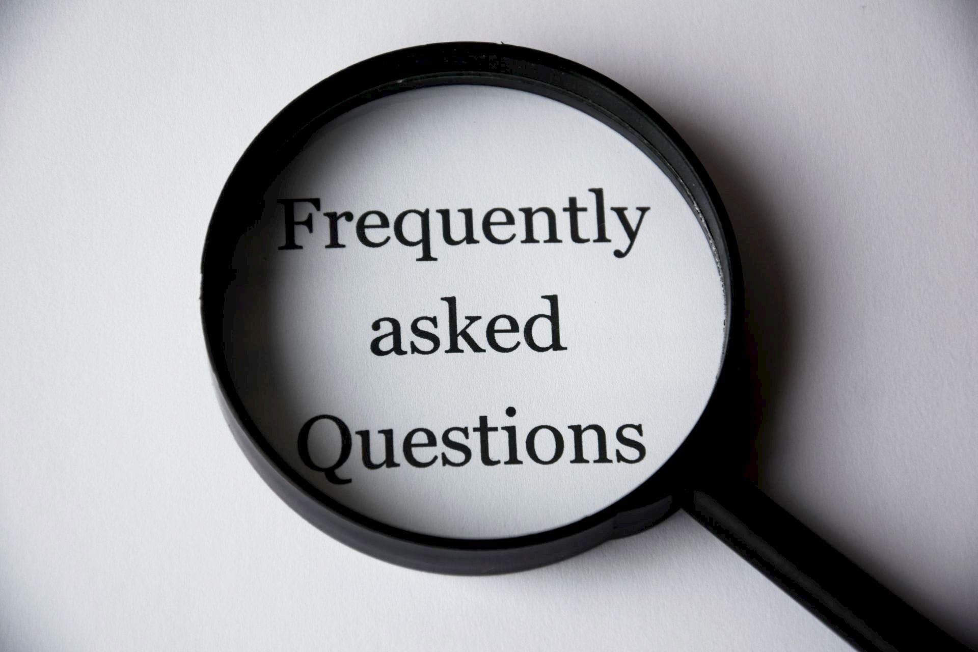 Frequently asked questions FAQs on paper looking through black magnifying glass